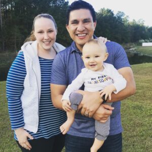 A family photo of Meagan Hernandez at Thanksgiving. Meagan is pictured with her spouse and baby.