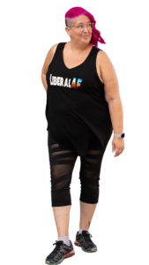 A full body photo of Meg looking up and to the right. Her hot pink hair is shaved on the side and her black top says "Liberal AF."