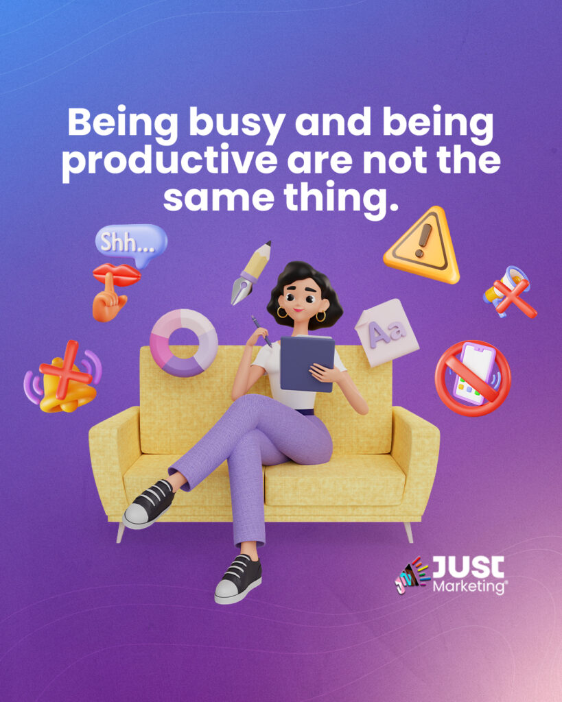 Illustration of a person with black hair sitting on a yellow couch, holding a clipboard and pen. Surrounding them are floating icons including a warning sign, pencil, life preserver, muted sound symbol, and a ‘no phones’ symbol. Text above reads: ‘Being busy and being productive are not the same thing.’ The Just Marketing logo appears at the bottom right. Background is a blue to purple gradient.